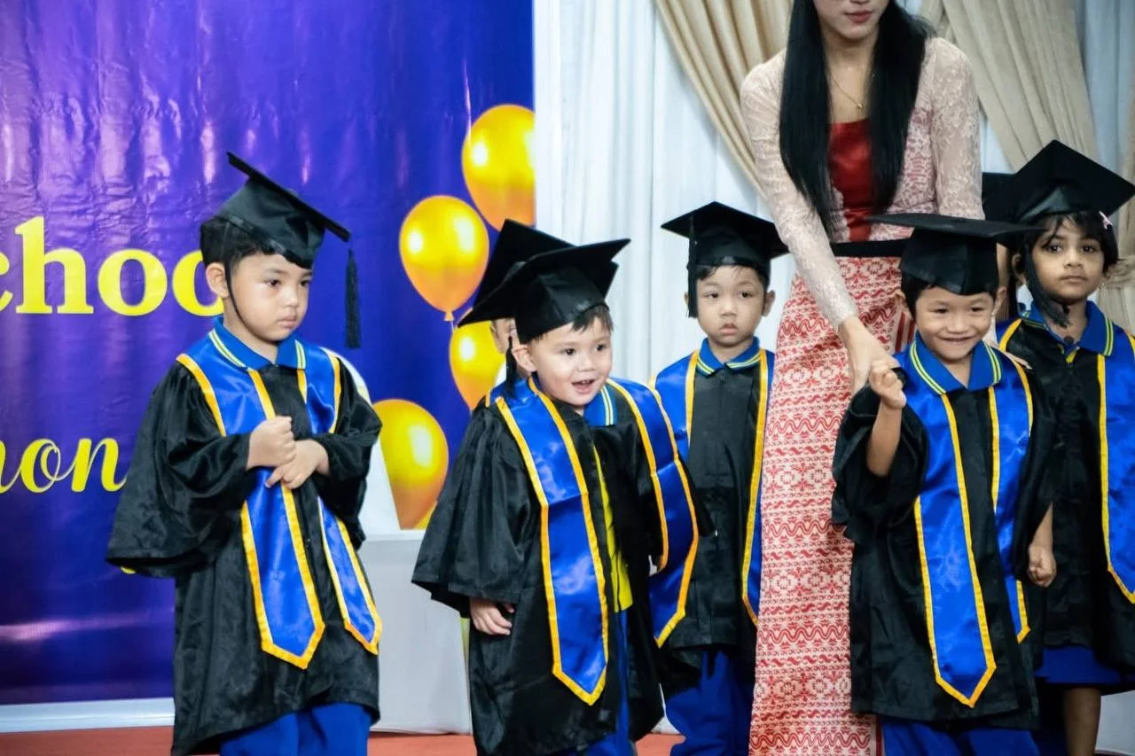 Young graduates standing together with a teacher at a school celebration